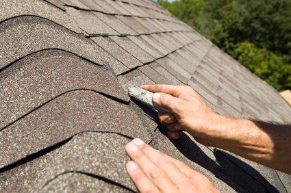 Roofer working on asphalt shingle roof.